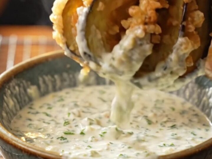 Golden accordion eggplant fries with garlic yogurt dip on a wooden board
