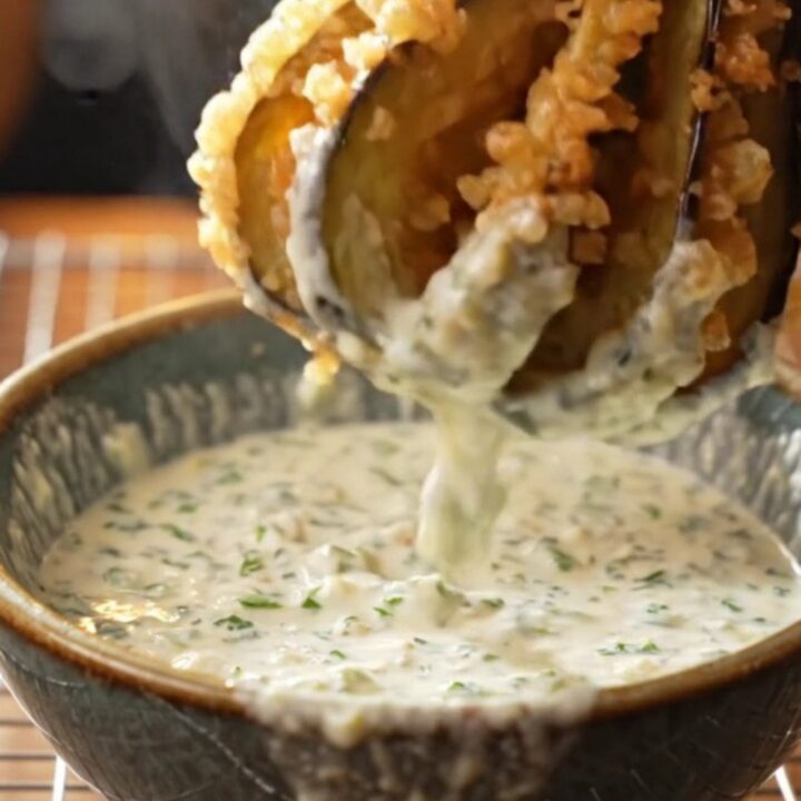 Golden accordion eggplant fries with garlic yogurt dip on a wooden board