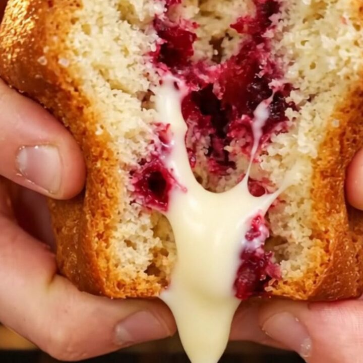 Tall bakery-style muffin with golden crunchy top, showing juicy strawberries and melted white chocolate inside
