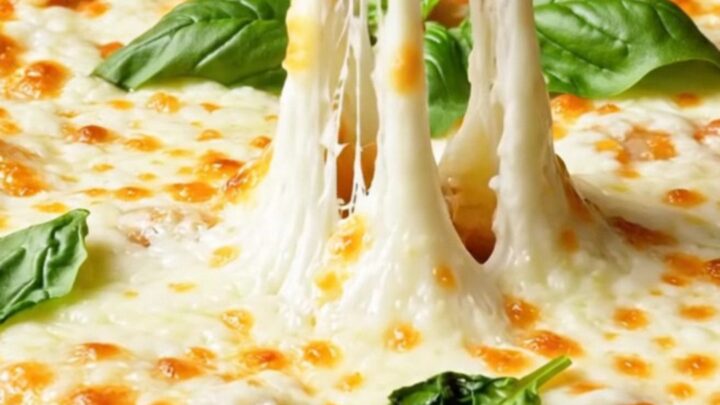 Spoon scooping creamy rigatoni with melted mozzarella pulling in long threads