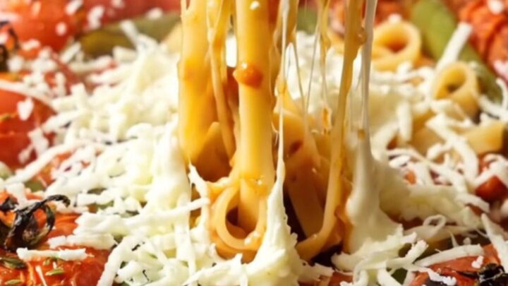 Tagliatelle pasta coated in roasted tomato sauce with melted mozzarella, topped with fresh basil in a skillet.