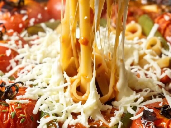 Tagliatelle pasta coated in roasted tomato sauce with melted mozzarella, topped with fresh basil in a skillet.
