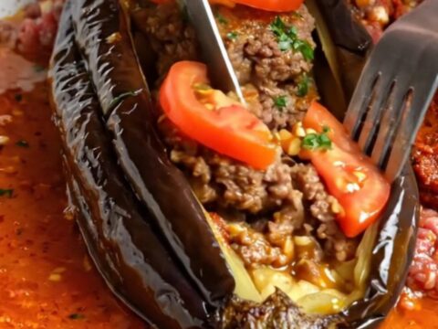 Whole roasted eggplant fanned out like an accordion, stuffed with spiced beef patties and tomato slices
