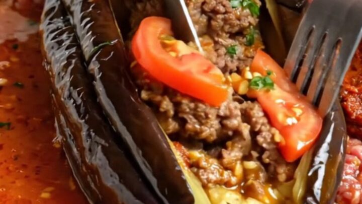 Whole roasted eggplant fanned out like an accordion, stuffed with spiced beef patties and tomato slices