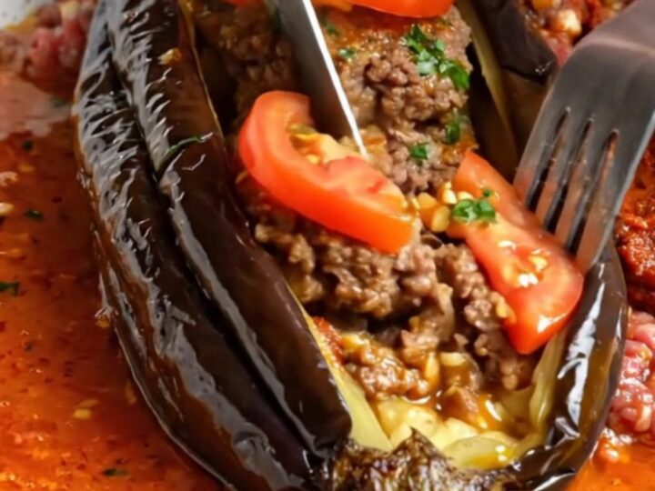 Whole roasted eggplant fanned out like an accordion, stuffed with spiced beef patties and tomato slices
