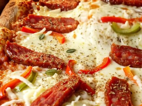 Fluffy Turkish sheet-pan pizza with melted mozzarella, sucuk slices, and bell peppers, cut into squares.