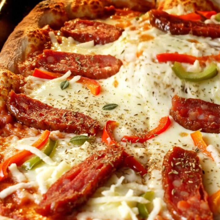 Fluffy Turkish sheet-pan pizza with melted mozzarella, sucuk slices, and bell peppers, cut into squares.