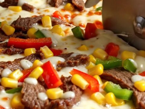 Sheet pan crepe pizza with melted cheese, sucuk, peppers, and corn, sliced into squares