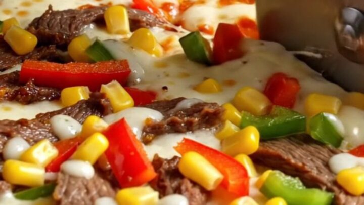 Sheet pan crepe pizza with melted cheese, sucuk, peppers, and corn, sliced into squares
