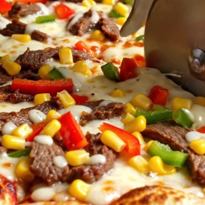 Sheet pan crepe pizza with melted cheese, sucuk, peppers, and corn, sliced into squares