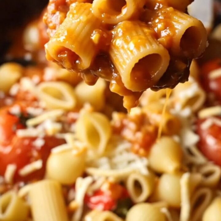 A rustic skillet filled with shell pasta coated in a chunky tomato and pepper sauce