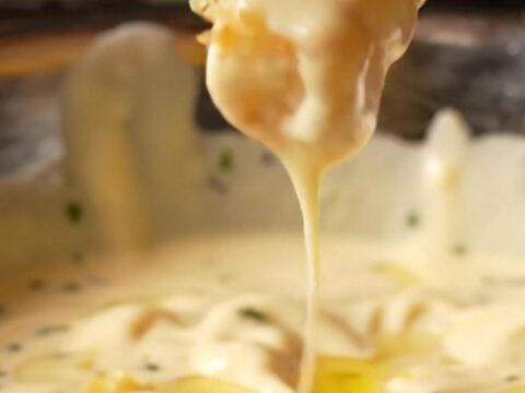 Golden crispy fries tossed with garlic butter and Parmesan, with a bowl of creamy garlic aioli for dipping.