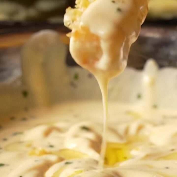 Golden crispy fries tossed with garlic butter and Parmesan, with a bowl of creamy garlic aioli for dipping.
