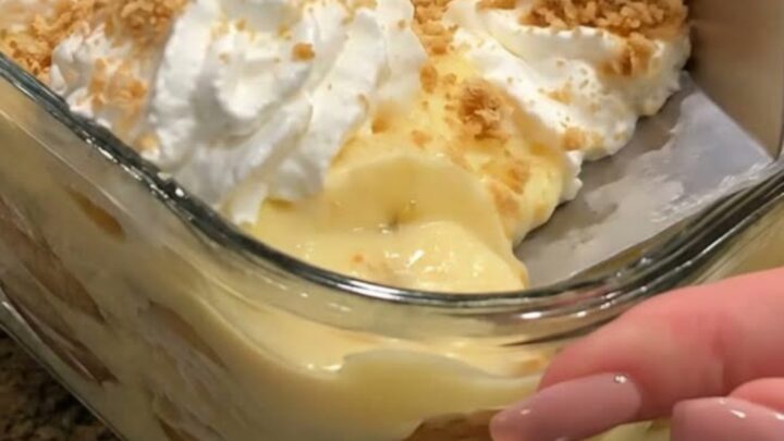 A clear glass square dish filled with layers of creamy vanilla pudding, fresh banana slices, and crisp vanilla wafers.