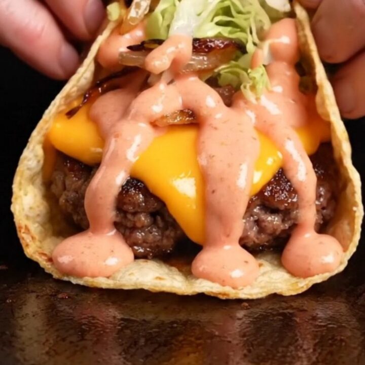 Smash burger tacos with crispy beef, melted cheddar, lettuce, and secret sauce on a plate