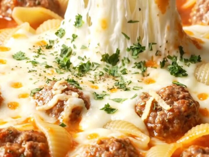 One-pan cheesy meatball shell pasta in a skillet, with melted mozzarella and parsley
