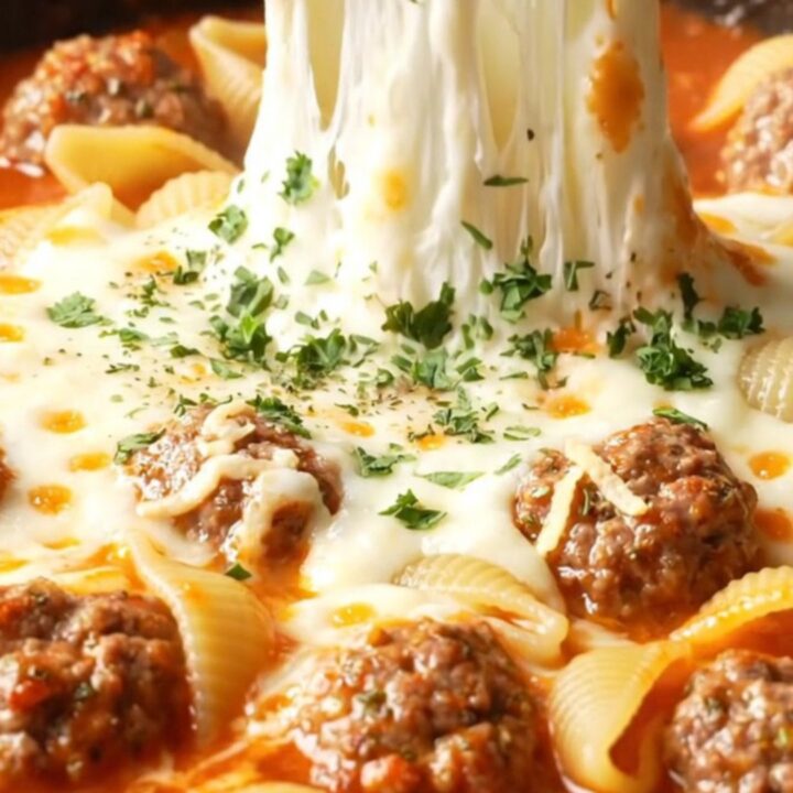 One-pan cheesy meatball shell pasta in a skillet, with melted mozzarella and parsley