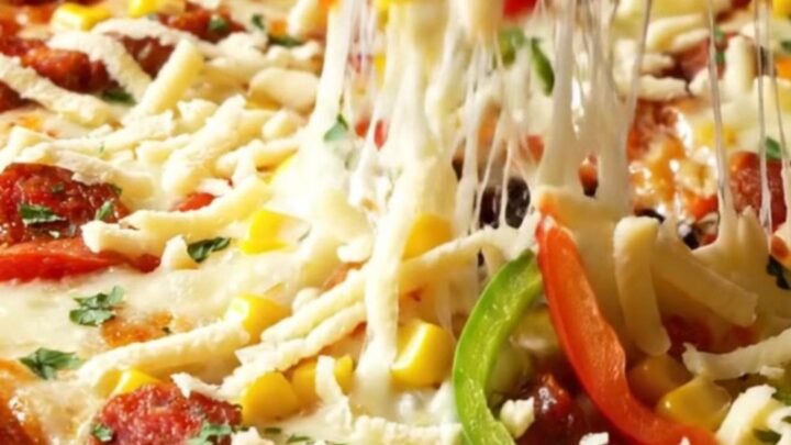 Golden sheet pan crepe pizza with melted cheese, sucuk, corn, and peppers, cut into squares
