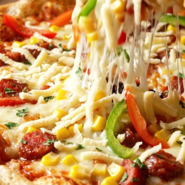 Golden sheet pan crepe pizza with melted cheese, sucuk, corn, and peppers, cut into squares