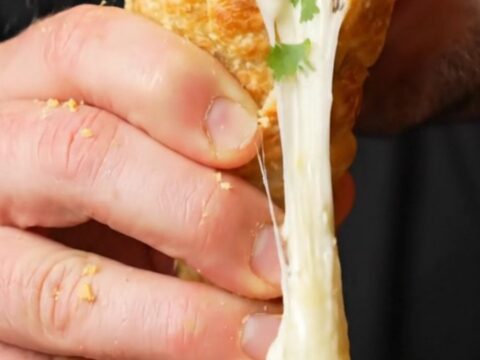 Crispy golden tortilla cone filled with seasoned beef and melted mozzarella, cheese pulling as it's lifted