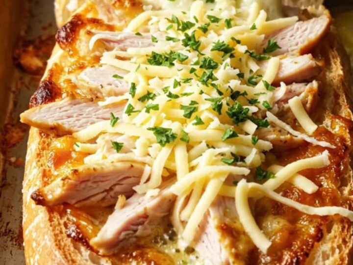 Cheesy chicken alfredo garlic bread with melted mozzarella pull, on a baking sheet