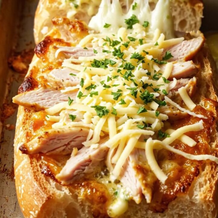 Cheesy chicken alfredo garlic bread with melted mozzarella pull, on a baking sheet