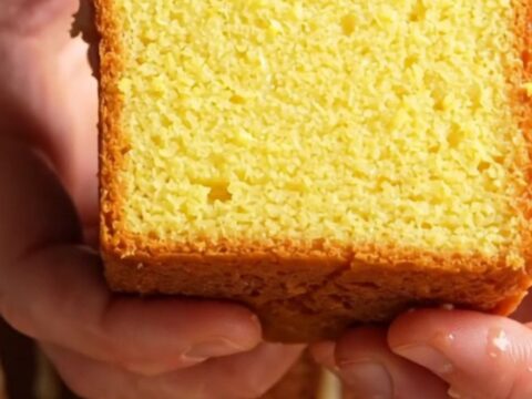 Whole lemon loaf cake with white glaze and lemon zest on a cooling rack