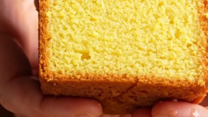 Whole lemon loaf cake with white glaze and lemon zest on a cooling rack