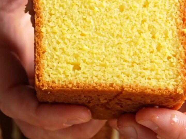 Whole lemon loaf cake with white glaze and lemon zest on a cooling rack