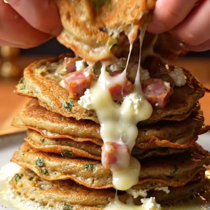 Stack of golden savory pancakes with melted feta and sucuk, garnished with fresh dill
