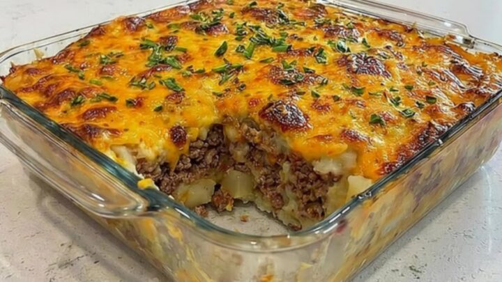 A hearty serving of loaded potato meatloaf casserole in a glass dish with a gooey cheese pull.