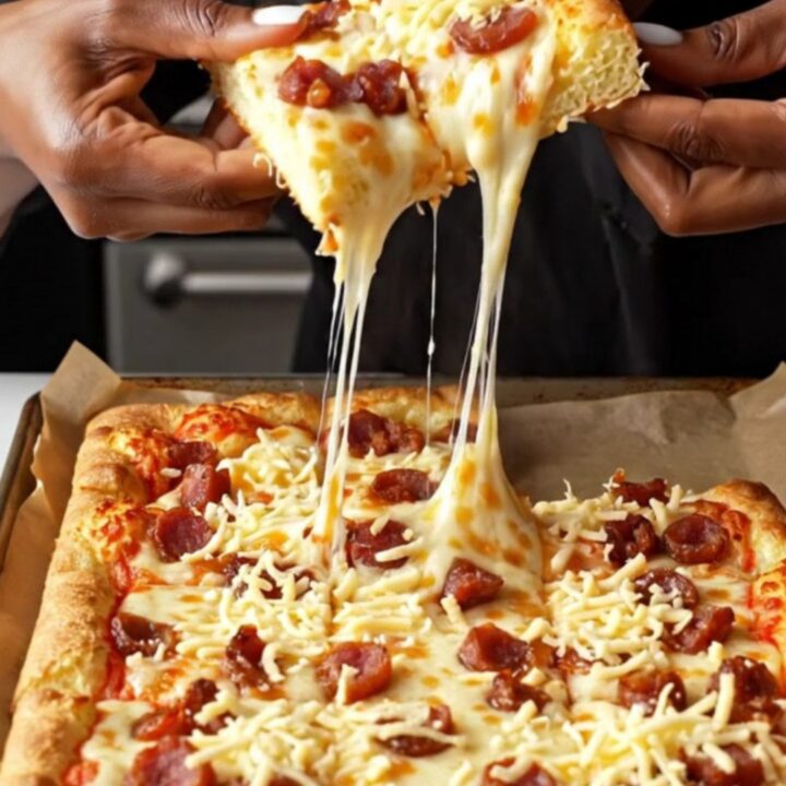 Golden sheet pan pizza cut into squares with melted cheese and crispy sucuk