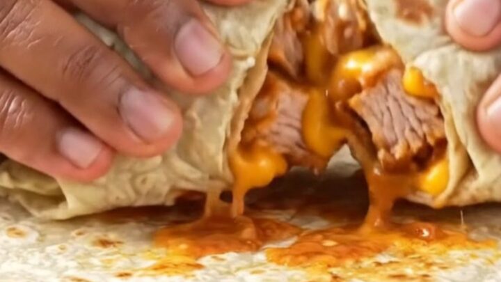 Crispy golden burrito sliced diagonally showing layers of chicken, lettuce, tomatoes, and melted cheese on a plate