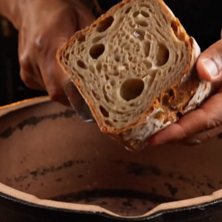 Crusty artisan sourdough loaf with deep mahogany crust and open crumb on a wooden board