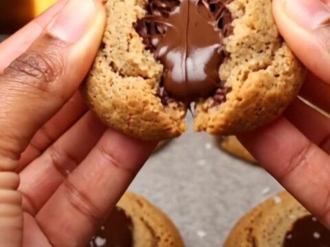 Soft-baked chocolate chip cookies on parchment paper with melted chocolate and flaky sea salt.