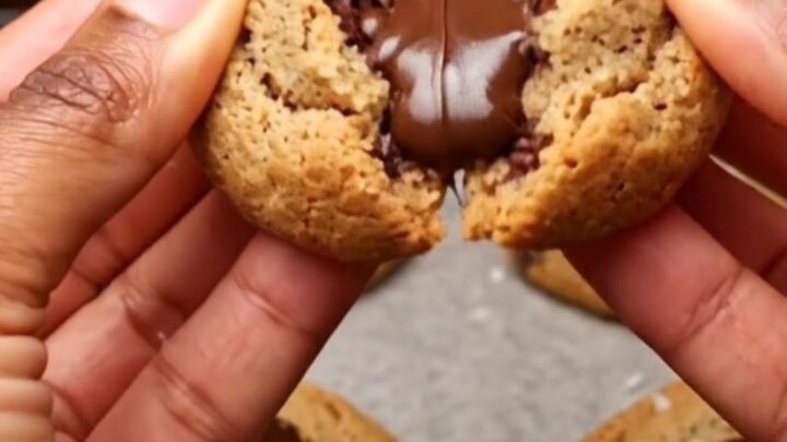 Soft-baked chocolate chip cookies on parchment paper with melted chocolate and flaky sea salt.