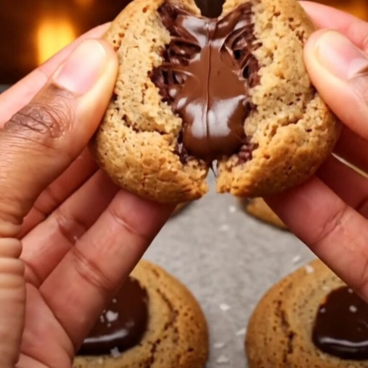 Soft-baked chocolate chip cookies on parchment paper with melted chocolate and flaky sea salt.