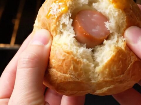 Golden bunny-shaped poğaça buns with sausage surprise on a baking sheet