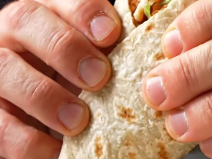 Crispy chicken Caesar wrap sliced diagonally, showing layers of golden chicken, lettuce, and creamy dressing