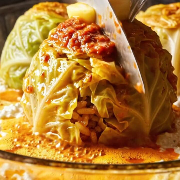 Golden cup-molded Turkish stuffed cabbage rolls on a platter with garlic yogurt and paprika butter