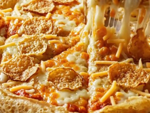 Golden puffy crepe pizza with melted cheese and crispy sucuk slices on a parchment-lined baking sheet.