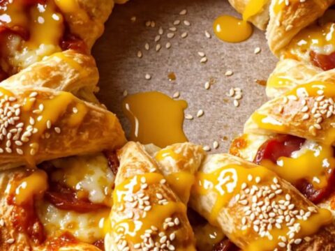 Golden crown pizza ring with sesame seeds and melted cheese on a baking sheet