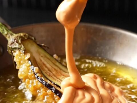 A golden crispy eggplant fan on a wire rack, sprinkled with sea salt and smoked paprika