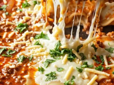 A bubbling skillet of lasagna with melted mozzarella and a lifted cheesy slice