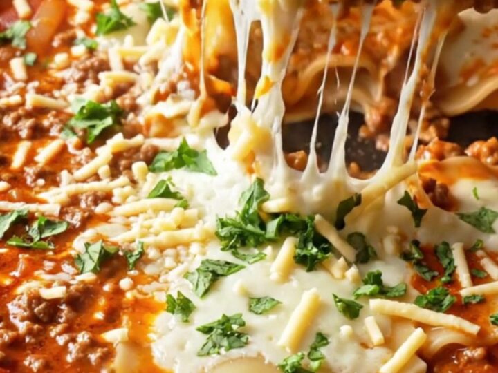 A bubbling skillet of lasagna with melted mozzarella and a lifted cheesy slice