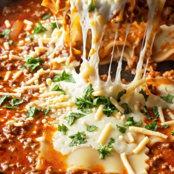 A bubbling skillet of lasagna with melted mozzarella and a lifted cheesy slice