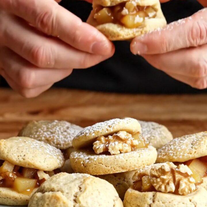 Golden toasted flour apple walnut cookies dusted with powdered sugar on a rustic plate