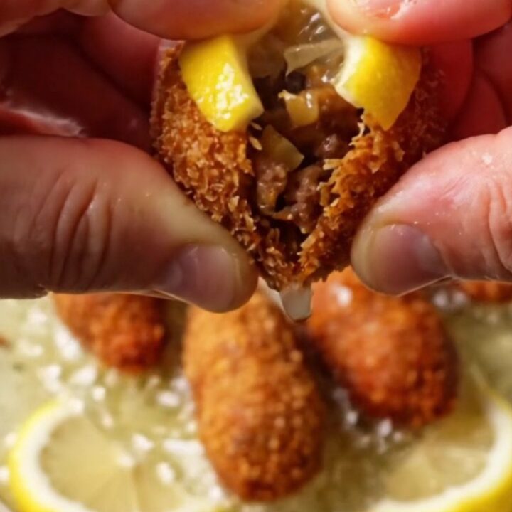 Golden crispy Turkish içli köfte on a platter with lemon wedges, showing a cracked shell with juicy filling
