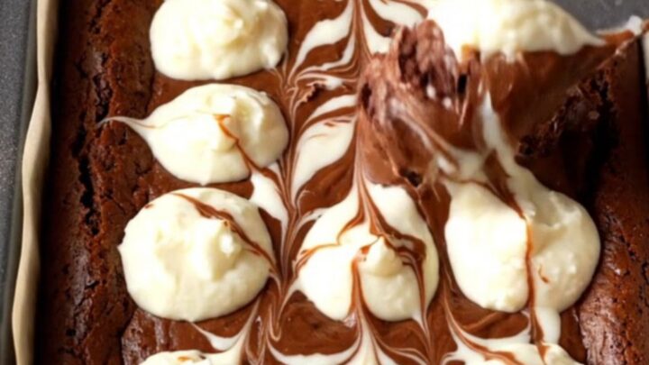 Fudgy cheesecake brownies with a marbled swirl, cut into squares and stacked on a plate.