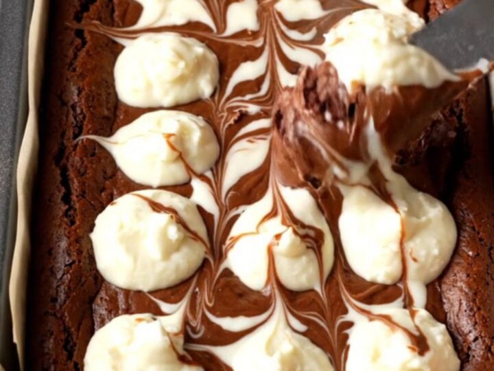 Fudgy cheesecake brownies with a marbled swirl, cut into squares and stacked on a plate.